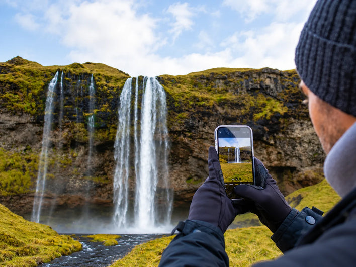 A person taking a waterfall photo with a smartphone, before turning the scene into canvas art.
